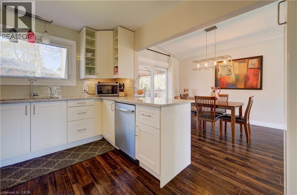 Kitchen featuring white cabinetry, light-toned countertops, a stainless steel dishwasher, wood-finish flooring, and a window above the sink - 172 Rennie Drive, Kitchener, ON - Indoor Photo Showing Kitchen