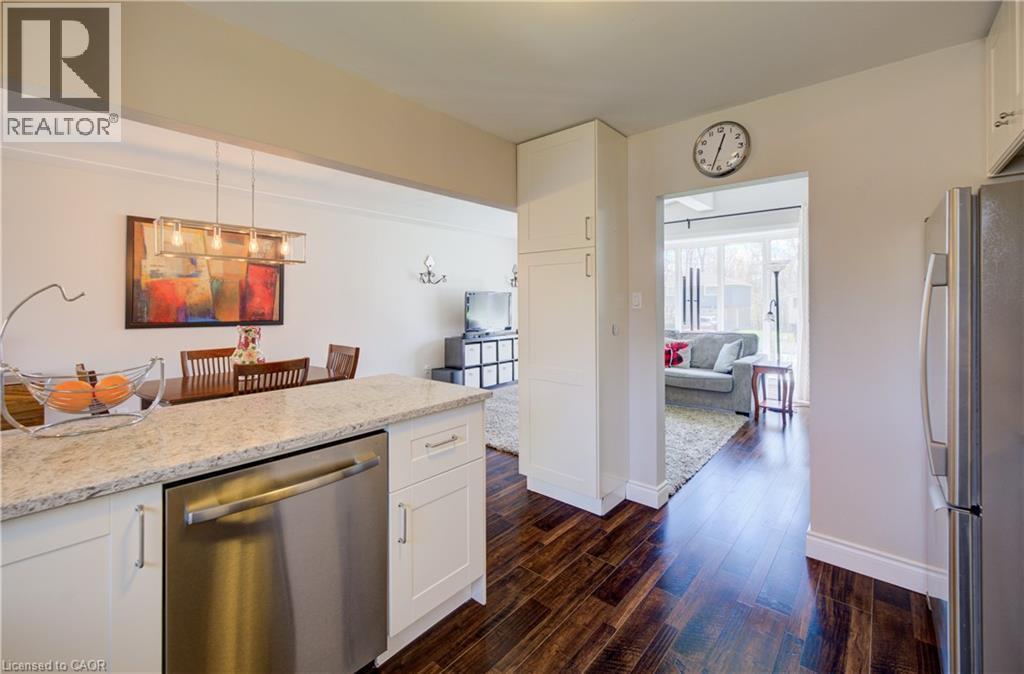Kitchen featuring granite countertops, white cabinetry, stainless steel dishwasher, and rich wood-finish flooring - 172 Rennie Drive, Kitchener, ON - Indoor Photo Showing Kitchen