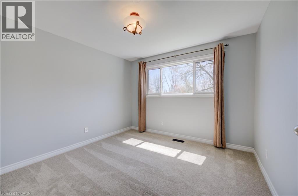 Neutral gray walls with white trim, light-colored carpeting, and a multi-pane window - 172 Rennie Drive, Kitchener, ON - Indoor Photo Showing Other Room
