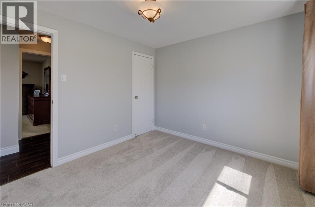 Neutral-toned room featuring light-colored carpeting, a standard white door, and white baseboards - 172 Rennie Drive, Kitchener, ON - Indoor Photo Showing Other Room