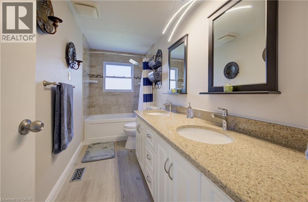 Dual vanity with integrated sinks and a speckled countertop, framed mirrors, and a tiled tub/shower combination with an opaque window - 172 Rennie Drive, Kitchener, ON - Indoor Photo Showing Bathroom