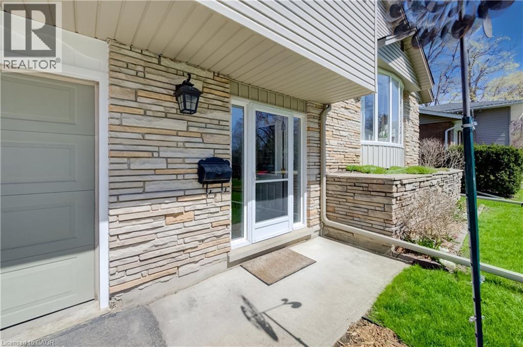 Stone veneer facade featuring a bay window, a concrete walkway, and a garage door - 172 Rennie Drive, Kitchener, ON - Outdoor With Exterior