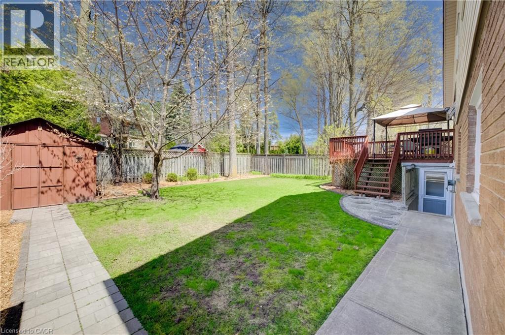 Expansive backyard featuring a lush lawn, a multi-level wood deck, a patio area, a shed, and mature trees - 172 Rennie Drive, Kitchener, ON - Outdoor
