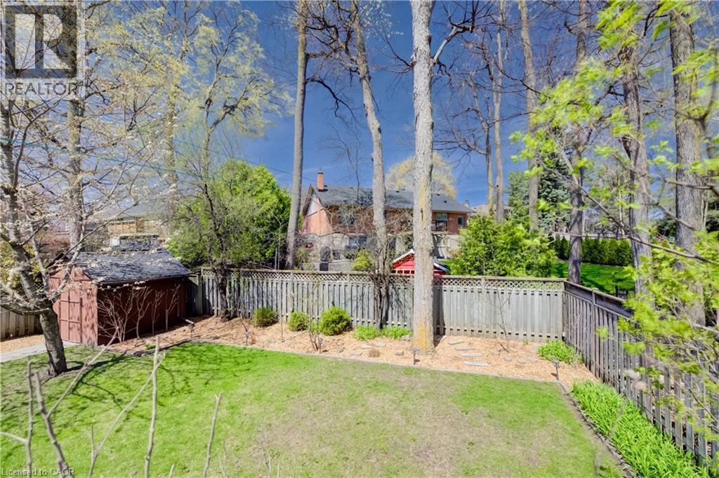 Expansive backyard featuring a lush lawn, mature trees, wood fence, garden shed, and varied landscaping - 172 Rennie Drive, Kitchener, ON - Outdoor