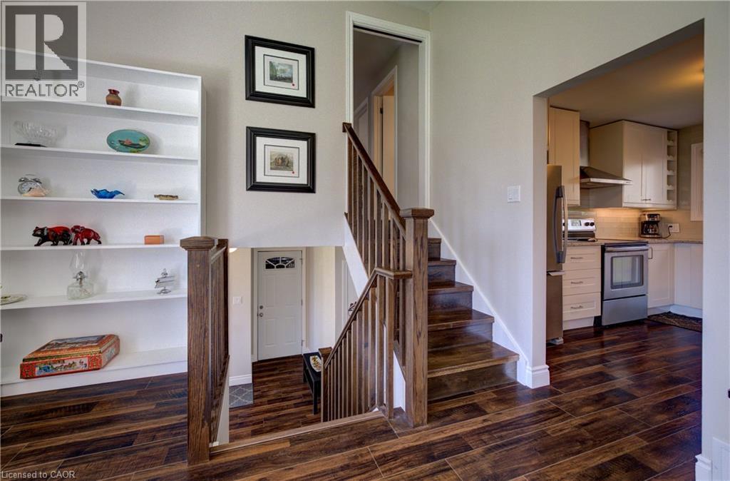 Rich wood-finish flooring throughout, featuring a hardwood staircase with matching banister and a built-in white shelving unit - 172 Rennie Drive, Kitchener, ON - Indoor Photo Showing Other Room