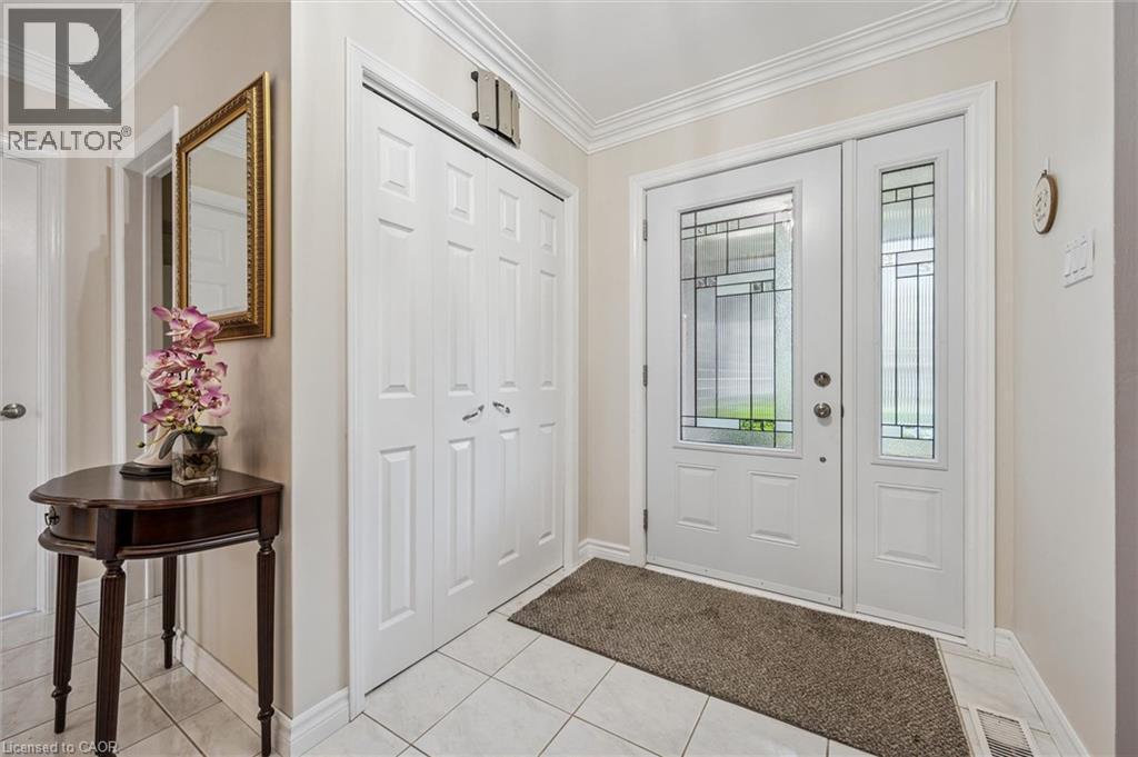 Brick exterior residence featuring a covered front porch, a two-car attached garage, a paved driveway, a manicured lawn, and established perimeter landscaping - 42 Trailview Drive, Kitchener, ON - Outdoor