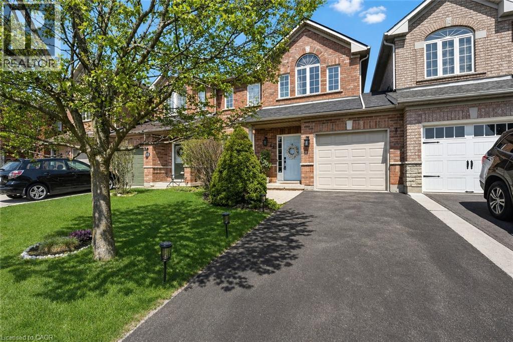 Brick facade home featuring a single-car garage, arched window, paved driveway, and manicured front lawn with mature tree - 62 Moore Crescent, Ancaster, ON - Outdoor With Facade