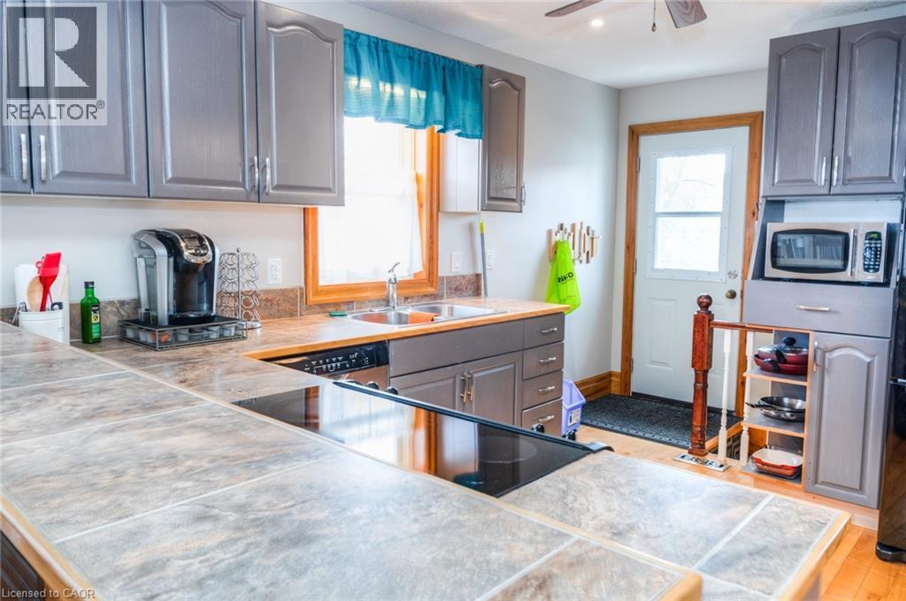 Kitchen featuring grey cabinetry, tile-finish countertops, stainless steel sink, and an integrated cooktop - 46 2 Avenue, Kitchener, ON - Indoor Photo Showing Kitchen With Double Sink