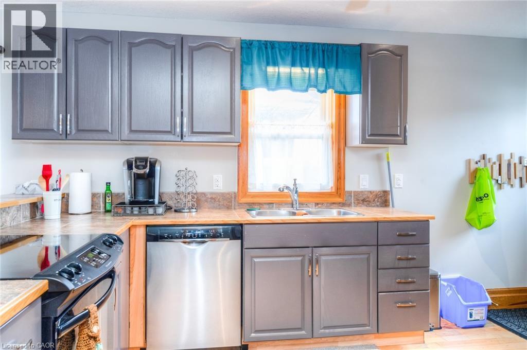 Kitchen featuring gray shaker-style cabinetry, wood-finish countertops, and a wood-framed window over the sink - 46 2 Avenue, Kitchener, ON - Indoor Photo Showing Kitchen With Double Sink