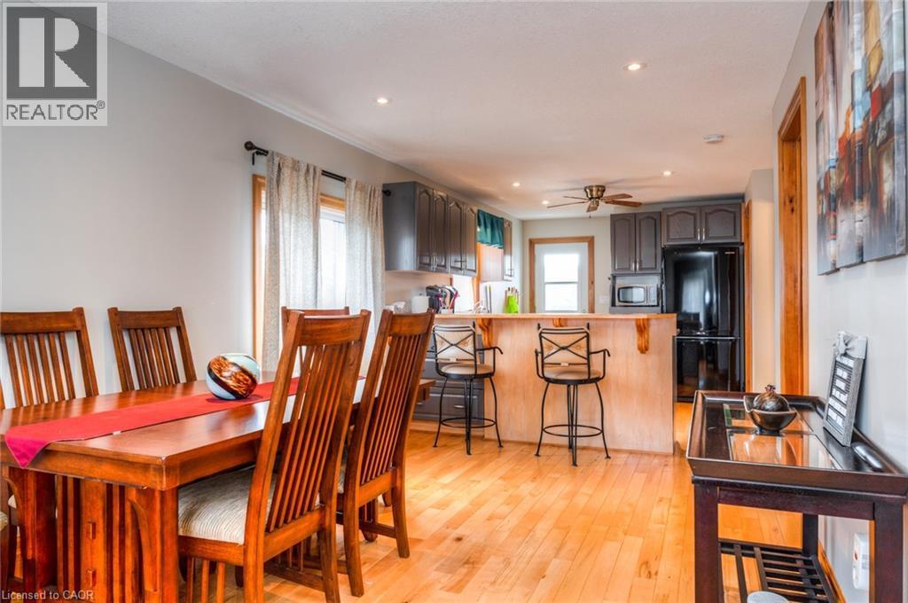 Open-concept kitchen and dining area featuring wood-finish flooring, recessed lighting, a breakfast bar, and dark-toned cabinetry - 46 2 Avenue, Kitchener, ON - Indoor Photo Showing Dining Room