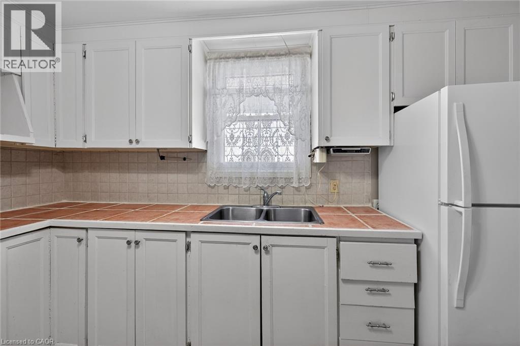 Kitchen featuring white cabinetry with silver hardware, square tile countertops, and a double basin stainless steel sink - 192 Ivon Avenue, Hamilton, ON - Indoor Photo Showing Kitchen With Double Sink
