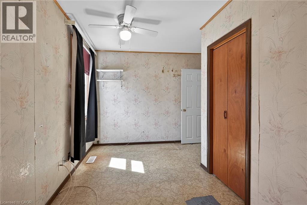 Room with patterned wallpaper, built-in closet with wood-finish bi-fold doors, a ceiling fan with light fixture, and a window with dark curtains - 192 Ivon Avenue, Hamilton, ON - Indoor Photo Showing Other Room
