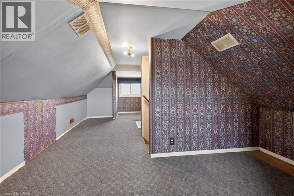 Carpeted attic space featuring sloped ceilings and patterned wallpaper - 192 Ivon Avenue, Hamilton, ON - Indoor Photo Showing Other Room