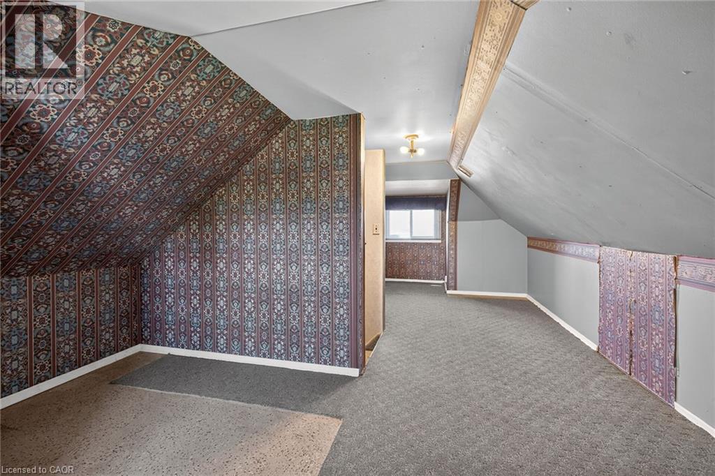 Attic space featuring sloped ceilings, patterned wallpaper accents, and a window for natural light - 192 Ivon Avenue, Hamilton, ON - Indoor Photo Showing Other Room
