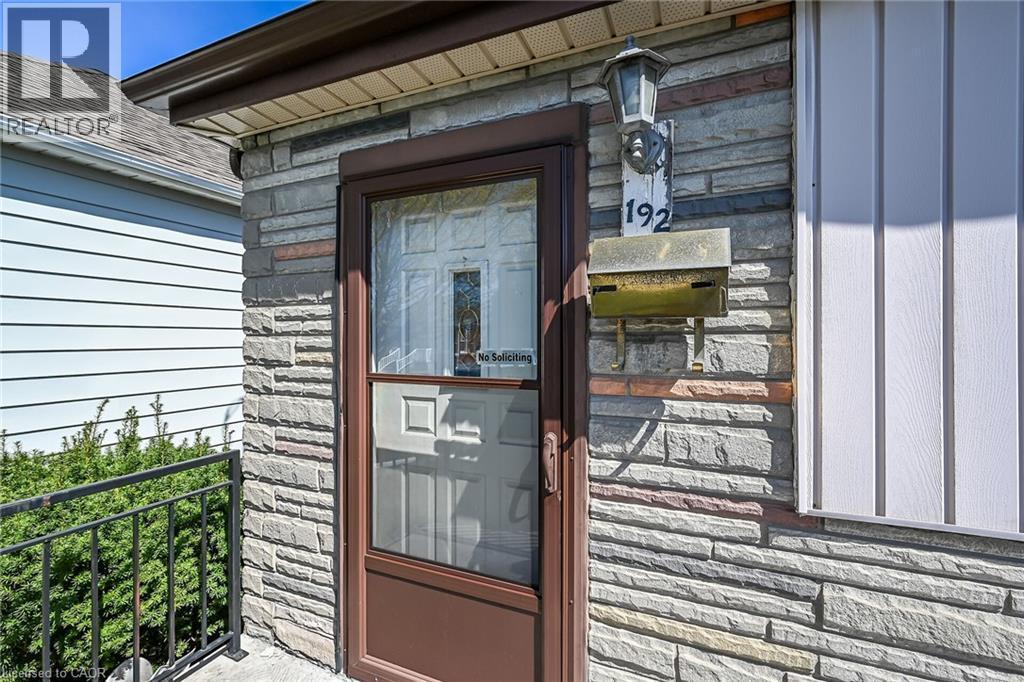 Stone veneer facade featuring a brown storm door and a traditional wall-mounted light fixture - 192 Ivon Avenue, Hamilton, ON - Outdoor