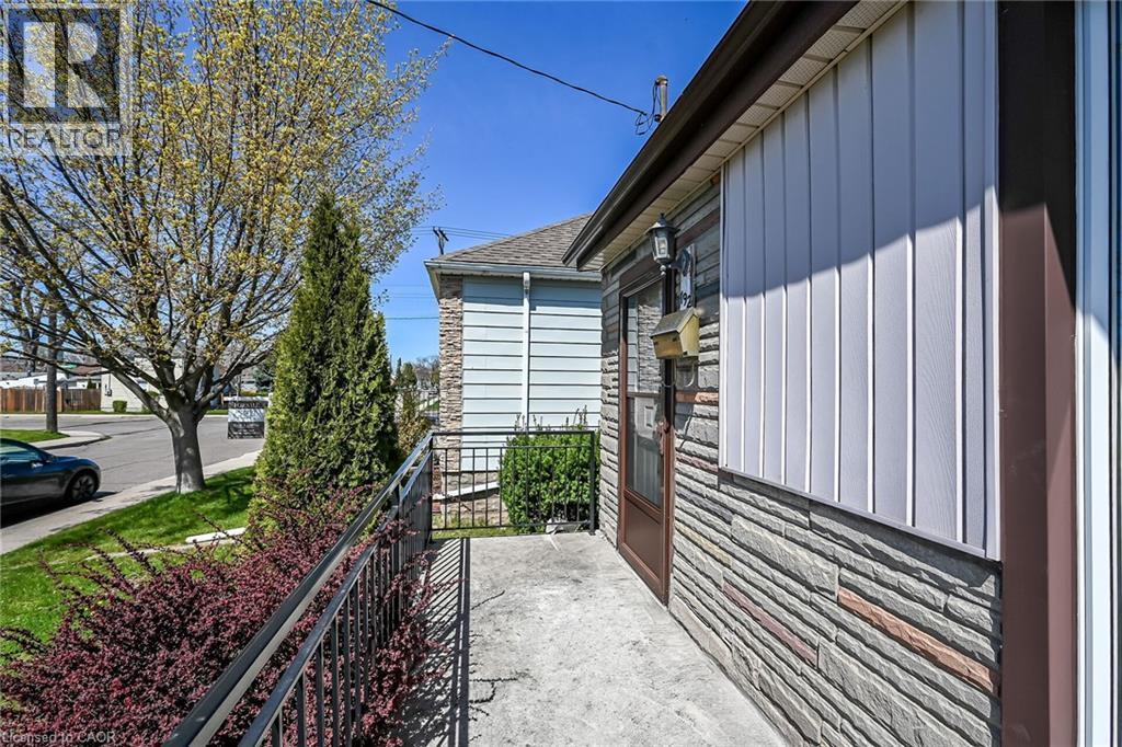 Concrete entryway with a metal railing, featuring stone veneer and vertical siding exterior finishes - 192 Ivon Avenue, Hamilton, ON - Outdoor