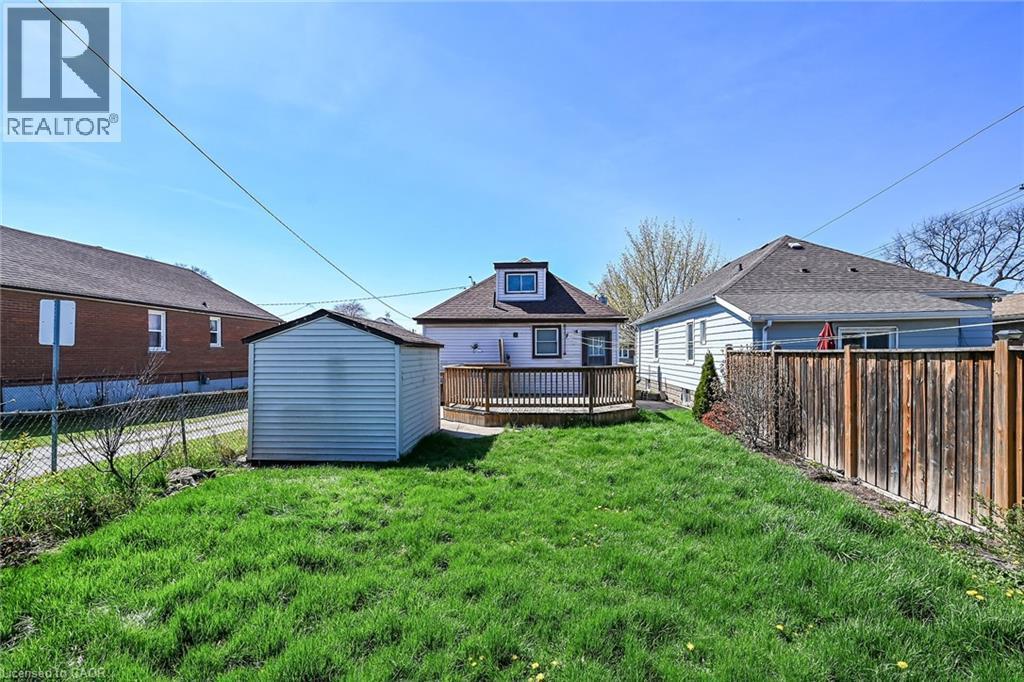 Expansive backyard featuring a green lawn, a wooden privacy fence, a storage shed, and a raised wooden deck - 192 Ivon Avenue, Hamilton, ON - Outdoor With Deck Patio Veranda With Exterior