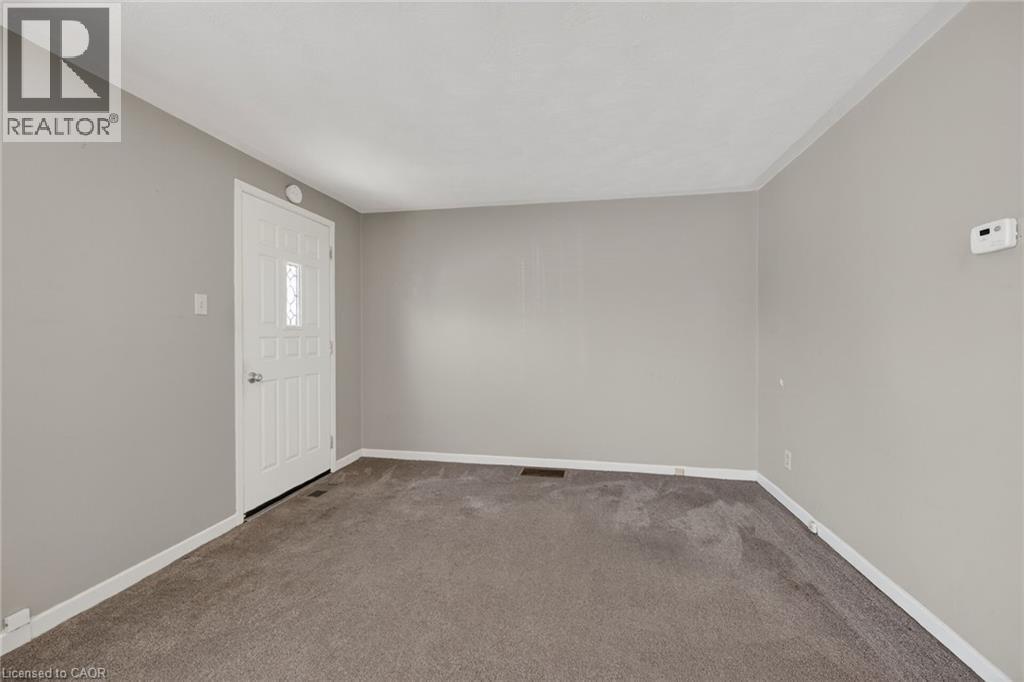 Spacious room with light gray walls, dark gray carpeting, and white baseboards - 192 Ivon Avenue, Hamilton, ON - Indoor Photo Showing Other Room