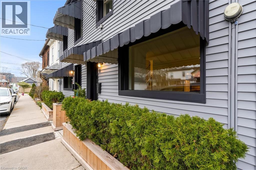 Street-facing exterior with horizontal siding and multiple black window awnings - 11 Ford Street, Hamilton, ON - Outdoor