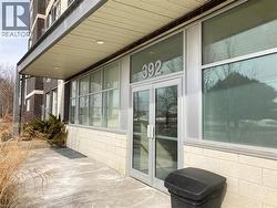 Building entrance featuring glass double doors, large storefront windows, and a protective overhead canopy with recessed lighting -