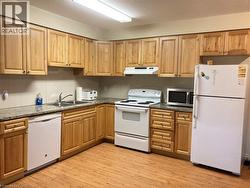 Kitchen featuring wood-finish cabinetry, granite-pattern countertops, and wood-finish flooring -