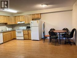 Kitchen area featuring light wood cabinetry, stone-finish countertops, and wood-finish flooring -