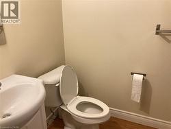 Hardwood-style flooring complementing a white pedestal sink and toilet -