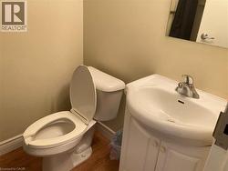 Compact bathroom featuring a white toilet, a white sink basin, and a chrome faucet -