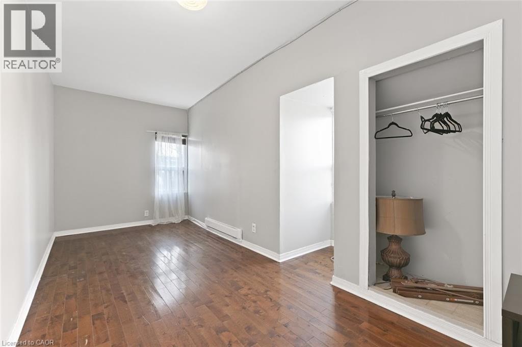 Room featuring wood-finish flooring, light grey painted walls, and white baseboards - 238-242 King Street E, Hamilton, ON