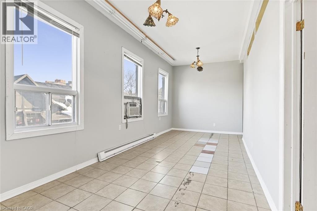 Spacious room with large windows, an in-wall air conditioning unit, and two ceiling-mounted light fixtures - 238-242 King Street E, Hamilton, ON