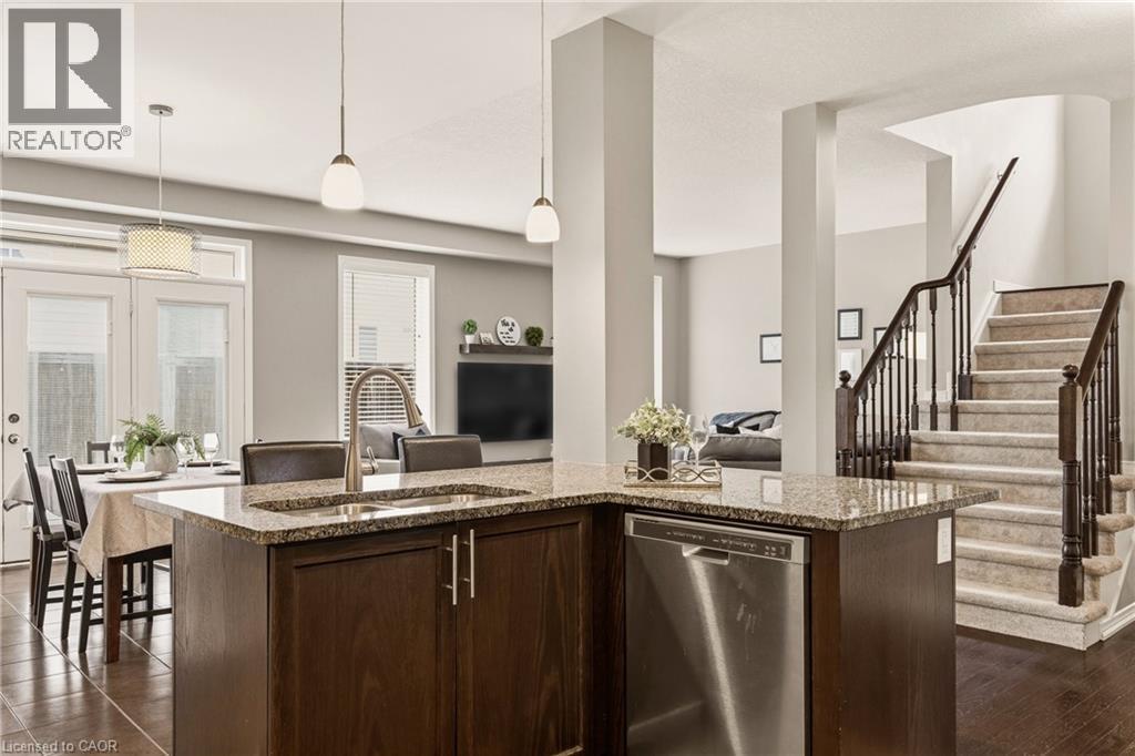 Kitchen island featuring a stainless steel dishwasher, granite countertop, and integrated sink with a gooseneck faucet - 42 Yager Drive, Binbrook, ON - Indoor Photo Showing Kitchen