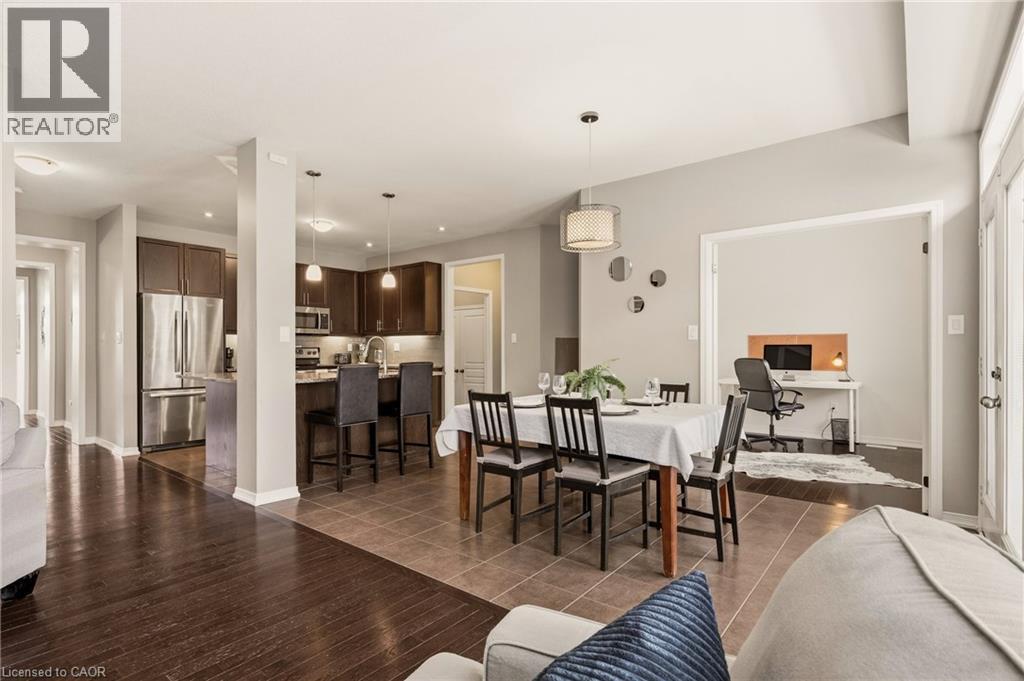 Open-concept living area featuring a dining space with a contemporary pendant light, a functional kitchen with dark wood-finish cabinetry and stainless steel appliances, and a dedicated room accessibl - 42 Yager Drive, Binbrook, ON - Indoor