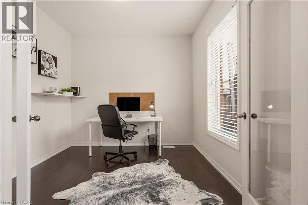 Dedicated interior space featuring dark wood-finish flooring, white walls, and a large window with white blinds - 42 Yager Drive, Binbrook, ON - Indoor