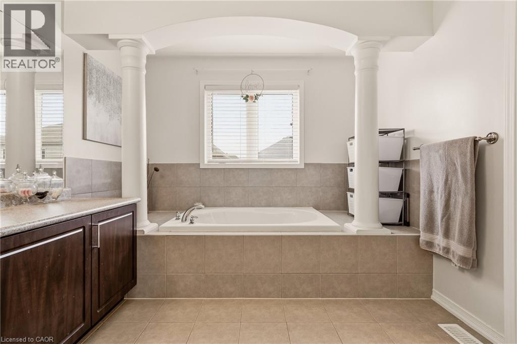 Soaking tub with chrome fixtures, surrounded by neutral tile and framed by decorative columns - 42 Yager Drive, Binbrook, ON - Indoor Photo Showing Bathroom