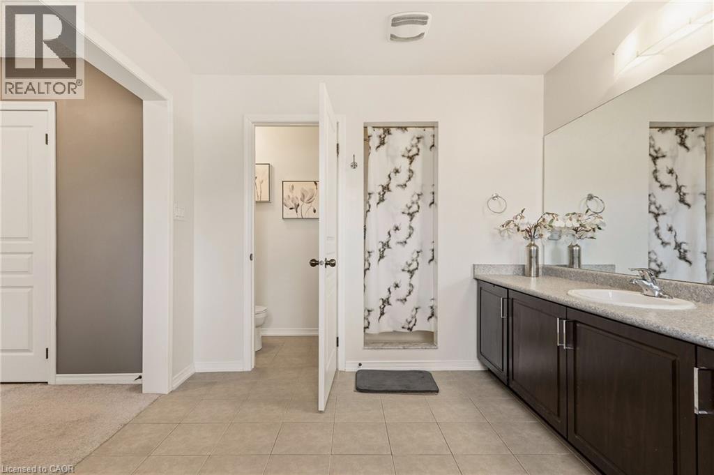 Bathroom featuring a dual-sink vanity with dark wood cabinetry, a light-toned countertop, and an integrated mirror - 42 Yager Drive, Binbrook, ON - Indoor Photo Showing Bathroom