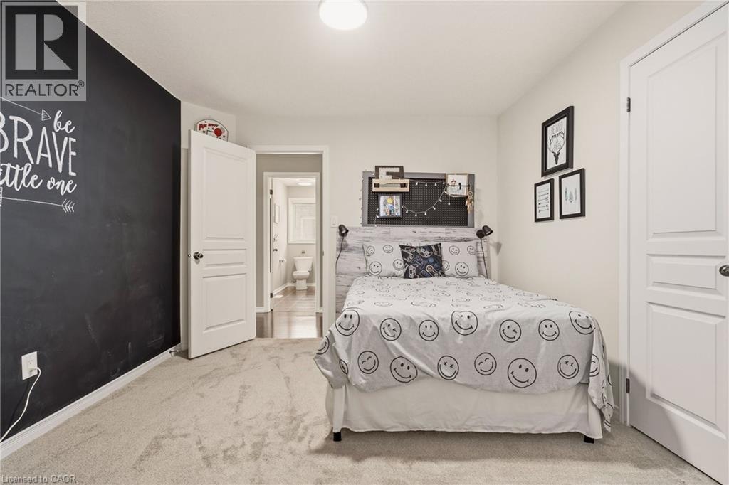 Carpeted bedroom featuring a chalkboard accent wall, white trim, and a three-panel interior door - 42 Yager Drive, Binbrook, ON - Indoor Photo Showing Bedroom