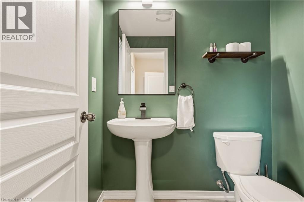 Pedestal sink with a matte black faucet, wall-mounted mirror, and decorative shelving - 42 Yager Drive, Binbrook, ON - Indoor Photo Showing Bathroom
