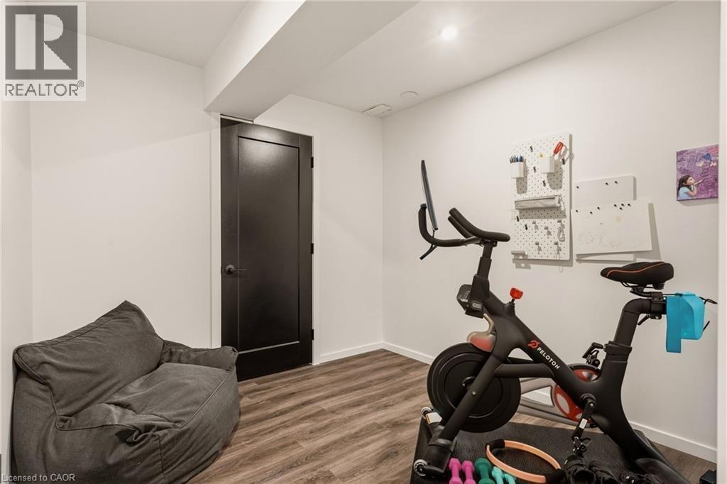 Room featuring wood-finish flooring, a dark-paneled door, and recessed lighting - 42 Yager Drive, Binbrook, ON - Indoor Photo Showing Gym Room
