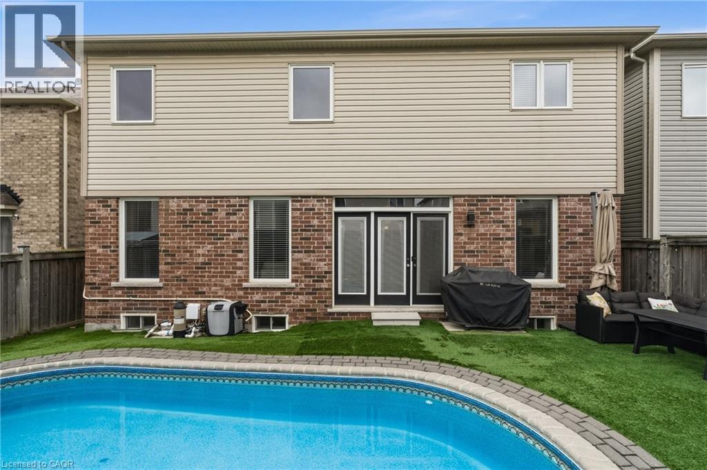 Backyard featuring a built-in swimming pool with paver coping, artificial turf, and a brick and siding exterior - 42 Yager Drive, Binbrook, ON - Outdoor With In Ground Pool With Exterior