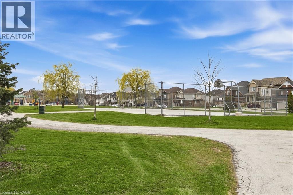 Outdoor recreational space featuring a basketball court, fenced perimeter, and a walking path surrounded by green grass - 42 Yager Drive, Binbrook, ON - Outdoor With View