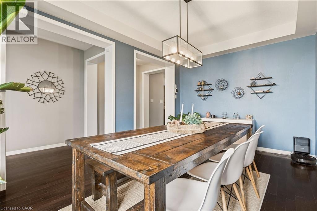 Dining area featuring dark wood-finish flooring and a contemporary linear chandelier - 42 Yager Drive, Binbrook, ON - Indoor Photo Showing Dining Room