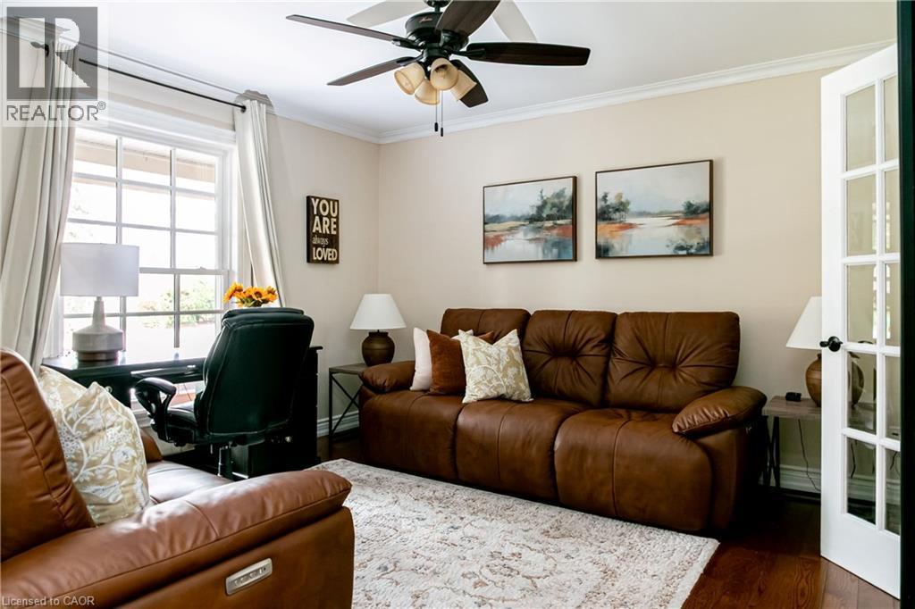 Bright interior room featuring a multi-pane window, crown molding, a ceiling fan with integrated lighting, and wood-finish flooring - 1577 Old Spar Court, Mississauga, ON - Indoor Photo Showing Living Room