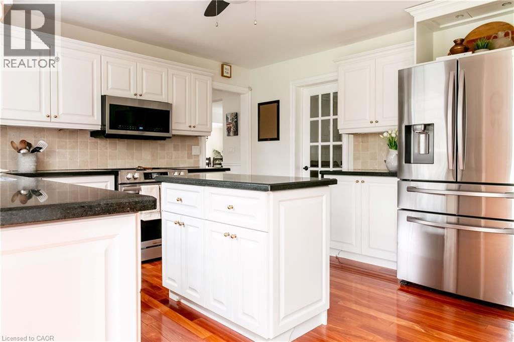 Kitchen featuring white cabinetry, dark countertops, stainless steel appliances, a tiled backsplash, and wood-finish flooring - 1577 Old Spar Court, Mississauga, ON - Indoor Photo Showing Kitchen With Stainless Steel Kitchen