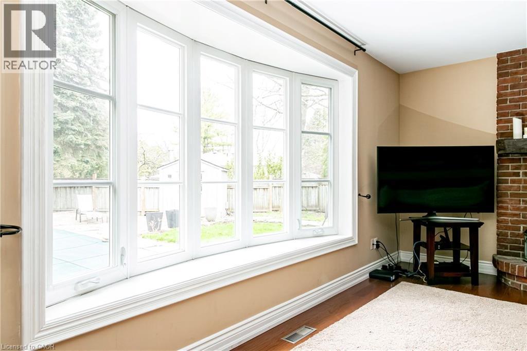 Expansive bay window with white trim, offering views of the rear yard and a covered pool area - 1577 Old Spar Court, Mississauga, ON - Indoor Photo Showing Other Room