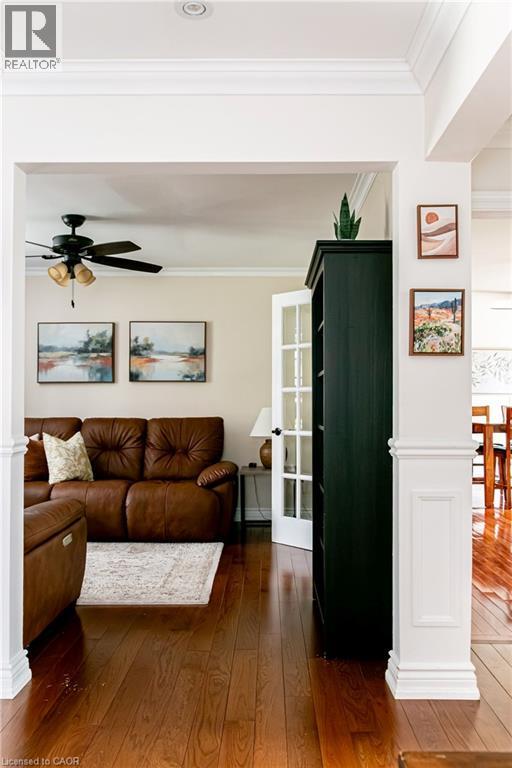 Warm wood-finish flooring extending into multiple spaces, framed by white architectural columns - 1577 Old Spar Court, Mississauga, ON - Indoor Photo Showing Living Room