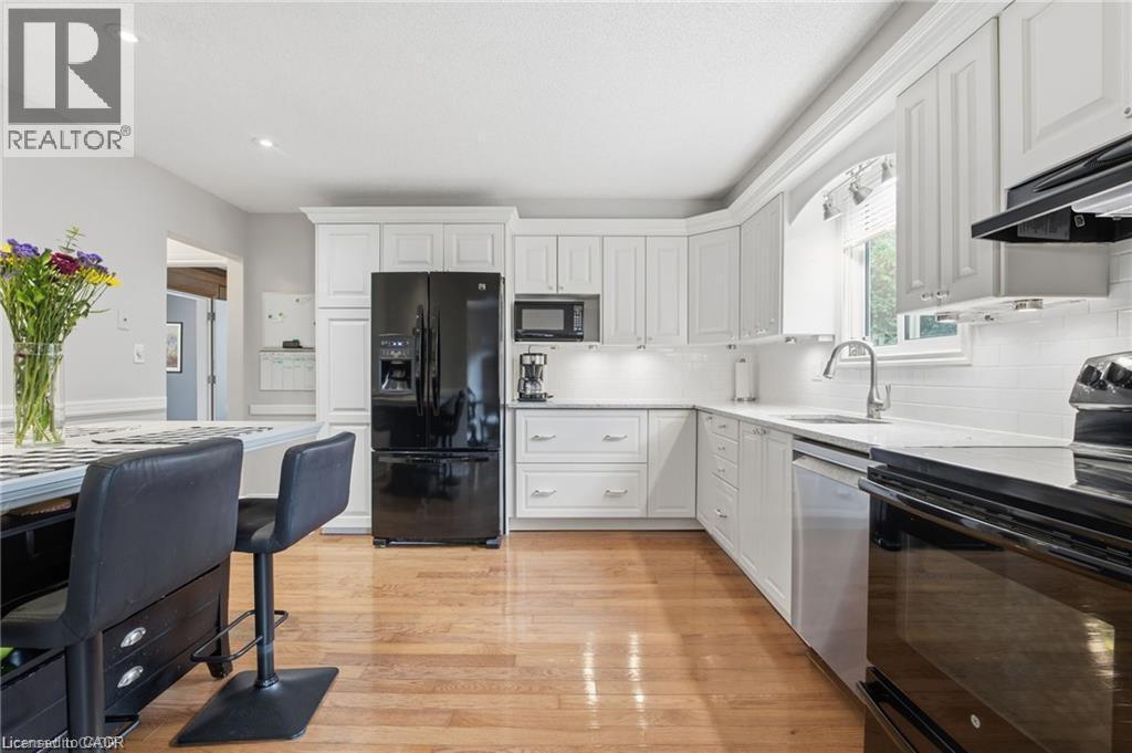 White eat-in kitchen with quartz and view to private backyard - 668 Tomahawk Crescent, Ancaster, ON - Indoor Photo Showing Kitchen With Upgraded Kitchen