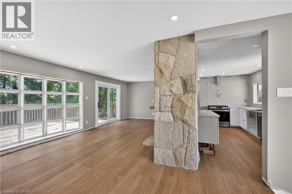Open-concept living area featuring wood-finish flooring, recessed lighting, and a stone-clad architectural pillar - 515 Bobbybrook Drive, London, ON - Indoor