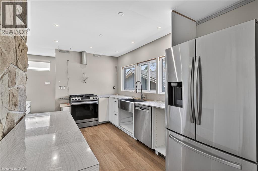 Kitchen featuring stone-clad accent wall, recessed lighting, and wood-finish flooring - 515 Bobbybrook Drive, London, ON - Indoor Photo Showing Kitchen With Upgraded Kitchen