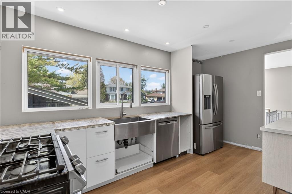 Kitchen featuring stainless steel appliances, a farmhouse sink, stone countertops, and recessed lighting - 515 Bobbybrook Drive, London, ON - Indoor Photo Showing Kitchen