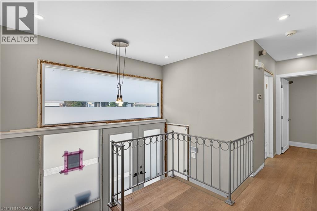 Second-story landing featuring wood-finish flooring, a metal railing, recessed lighting, and a pendant light fixture - 515 Bobbybrook Drive, London, ON - Indoor Photo Showing Other Room